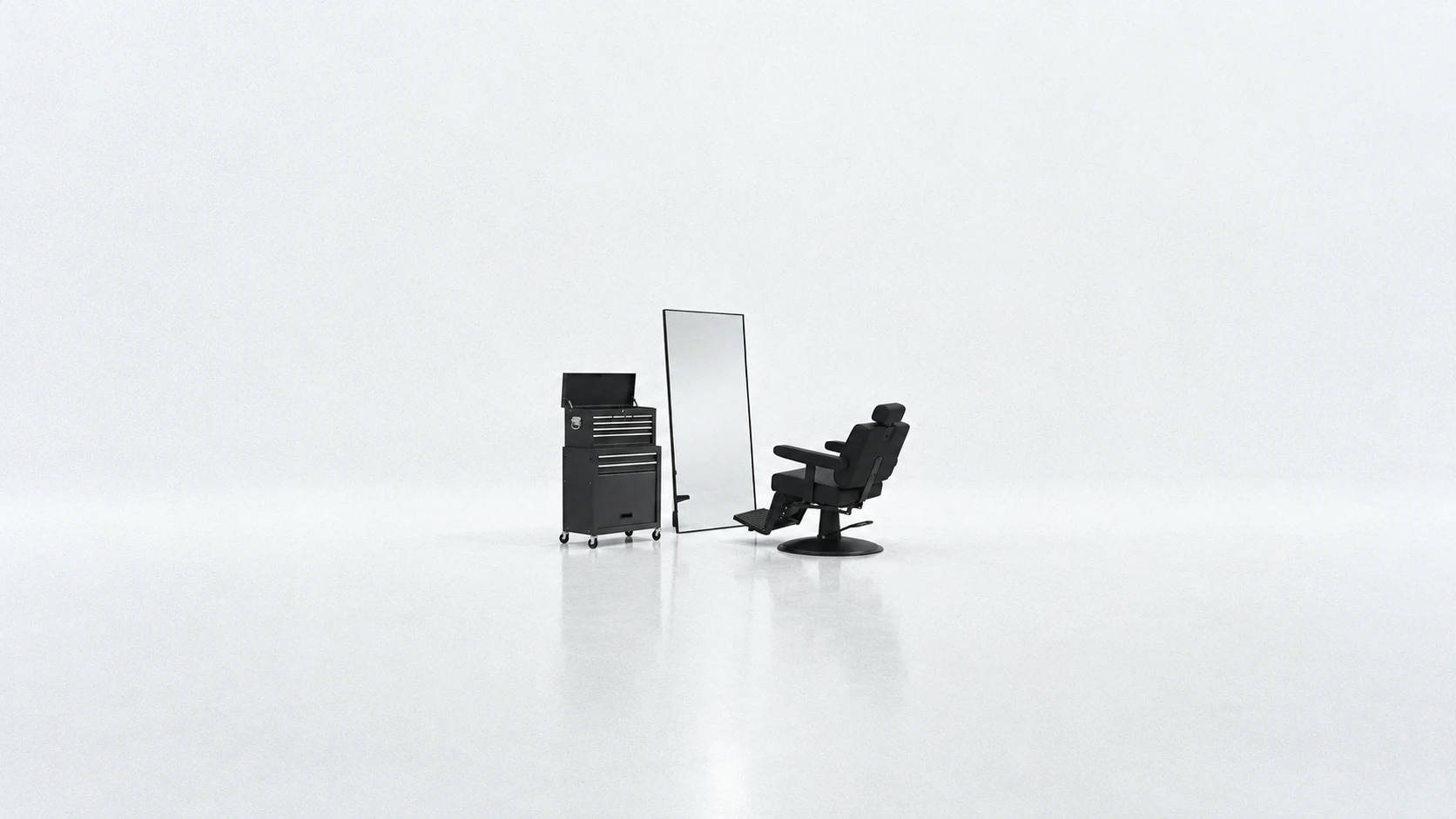 Cajonera negra, espejo de cuerpo entero y sillón de barbero en un estudio gris claro